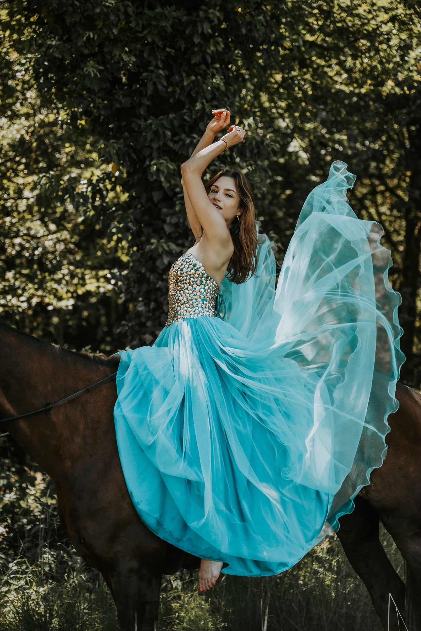 Vrouw in een turquoise jurk op een paard